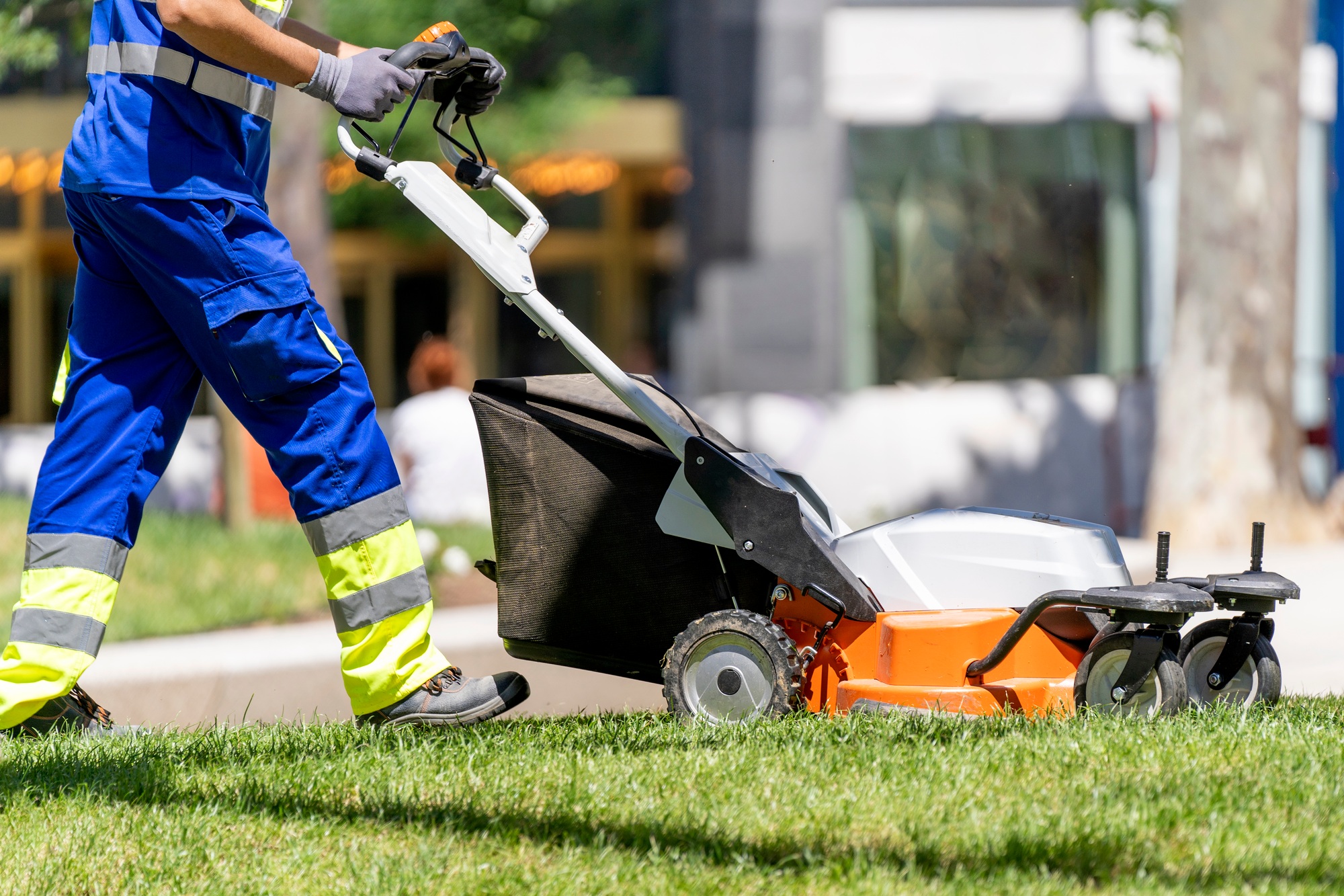 Garden worker mowing the lawn
