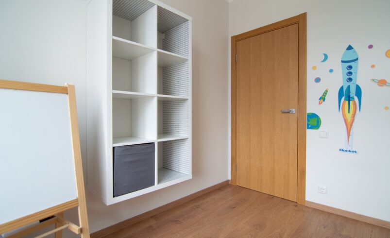 Children's room in a flat with a set of shelves and a white board